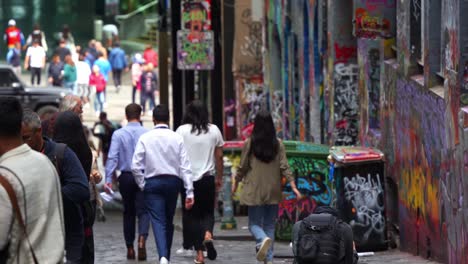 People-touring-at-Hosier-Lane-in-Melbourne-city,-a-popular-cobblestone-laneway-with-a-vibrant-array-of-art-murals-and-graffiti-on-the-exterior-walls-of-buildings,-a-creative-cultural-street-scene