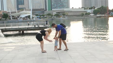 Madre-Joven-Levantando-A-Su-Bebé-Mientras-Se-Divierte-Con-Su-Familia-En-Marina-Bay-Singapur