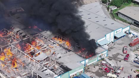 Bomberos-Intentan-Extinguir-Incendio-En-Fábrica-Textil-En-Santo-Domingo,-Aéreo