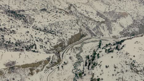 Tilt-up-drone-cinematic-footage-of-mountains-covered-in-snow-with-valley-of-Northern-Pakistan-Naltar-Valley-Gilgit