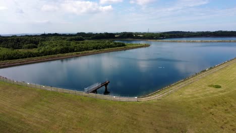 Aerial-view-circling-water-supply-reservoir-blue-sky-reflections-in-rural-countryside-lake