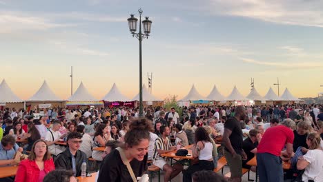 Attendees-happily-drink-and-eat-at-Praça-do-Comércio-Square,-Lisbon,-Portugal,-celebrating-the-Arraial-Lisboa-Pride