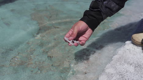 Man-extracting-salt-crystal-from-saltwater-pond-in-Salinas-Grandes-salt-flat