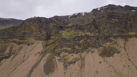 Aerial-landscape-view-of-icelandic-mountain-peaks,-with-melting-snow,-on-a-moody-evening