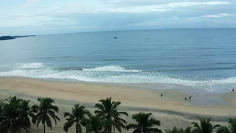 Lots-of-tourists-are-seen-on-the-beach,-wave-is-reaching-the-shore-and-there-are-boats