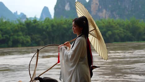 Hanfu-Model-Mädchen-Hält-Deng-Regenschirm-Und-Dreht-Ihn-Leicht,-Als-Würde-Ein-Vogel-Mit-Den-Flügeln-Schlagen