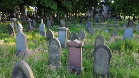 Antena-De-Un-Cementerio-Espeluznante-Y-Cubierto-De-Maleza-Con-Una-Iglesia-Al-Fondo