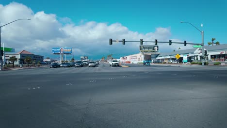 Las-Vegas-Wide-shot-of-a-commercial-strip-in-Las-Vegas,-featuring-palm-trees,-parked-cars,-and-storefronts-under-a-bright-blue-skysuburbs