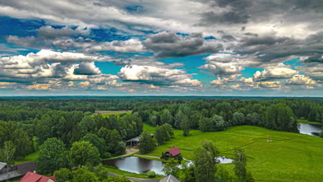 Bewegung-Der-Wolken-Auf-Der-Ländlichen-Landschaft-Mit-Dorf,-Grünen-Feldern-Und-Vegetation---Hyperlapse