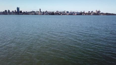 Drone-vie-and-Aerial-low-fly-over-the-ocean-and-slow-tilt-up-reveal-Maputo's-skyline