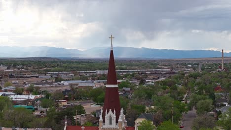 Drone-orbits-cross-and-brown-red-spire-tower-above-cathedral-in-Pueblo-Colorado