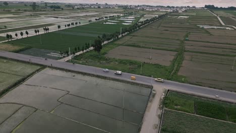 Aerial-footage-of-light-car-traffic-amidst-vast-crop-fields-in-Dali,-Yunnan-Province-in-China