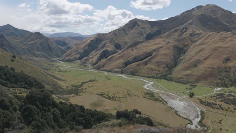 Wide-view-of-river-running-through-a-valley-between-mountains-on-a-sunny-summer-day-at-Moke-Lake,-Queenstown,-New-Zealand