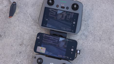 Grey-drone-controller-with-a-smartphone-attached-showcasing-the-camera-view,-resting-on-a-stone-surface,-depicting-modern-drone-technology-and-outdoor-usage