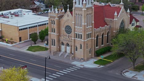 Drone-orbits-front-of-cathedral-church-in-Pueblo-Colorado-as-cars-drive-along-street