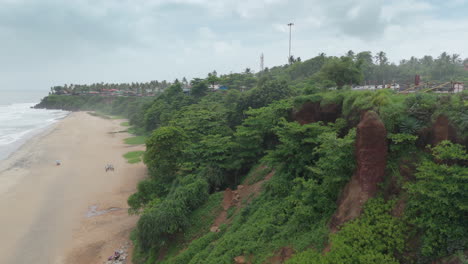 Shoreline-of-Varkala-Cliff-Beach,-drone-view-of-Varkala-beach-from-the-top-of-the-cliff-also-known-as-Papanasham-Beach,-Thiruvananthapuram,-Kerala,-India