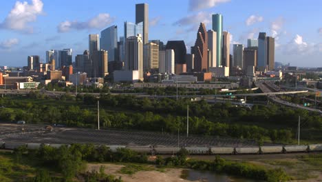 Establishing-shot-of-downtown-Houston,-Texas-on-cloudy-but-sunny-day-as-train-passes-by