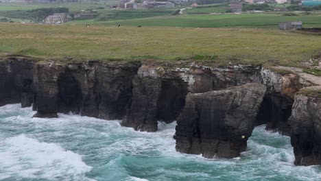 Waves-crashing-through-rock-arches-on-As-Catedrais-,-Cathedrals-beach-Northern-Spain-drone,aerial