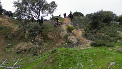 Vuelo-Con-Drones-En-Un-Campeonato-De-Motocross-Al-Aire-Libre-Donde-El-Piloto-Esta-En-Accion-En-El-Circuito-Que-Esta-Marcado,-Subiendo-Y-Bajando,-Bien-Ejecutado,-Hay-Gente-Mirando-Y-Disfrutando