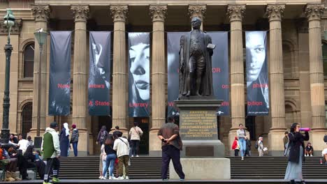 The-grand-front-facade-of-the-State-Library-Victoria-with-distinctive-octastyle-portico-with-its-fine-Corinthian-columns,-featuring-the-statue-of-Sir-Redmond-Barry-located-on-the-forecourt