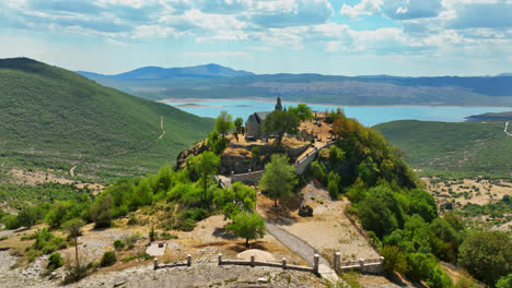 Aerial-view-away-from-the-Crkva-Na-Valu-Vracenovici-church,-in-sunny-Montenegro