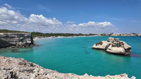 Timelapse-at-Spiaggia-delle-Due-Sorelle-in-the-Lecce-region,-surrounded-by-turquoise-waters-and-sandy-beaches,-with-fast-moving-clouds,-Italy