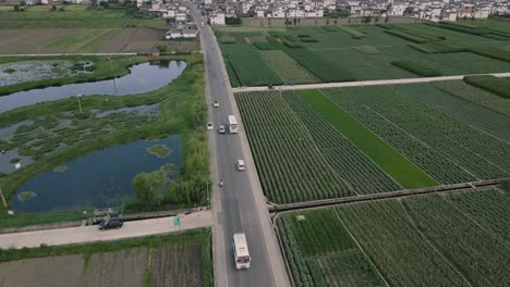 Panning-aerial-footage-of-light-car-traffic-amidst-vast-crop-fields-in-Dali,-Yunnan-Province-in-China