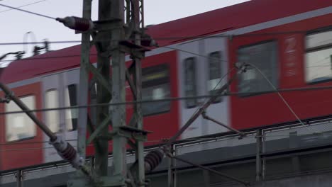 Red-Deutsche-Bahn-train-passing-behind-steel-power-lines