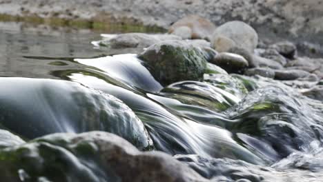 Close-up-shot-of-water-flowing-between-rocks-in-natural-pools-of-a-river
