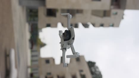 Drone-in-mid-flight,-surrounded-by-modern,-multi-story-buildings-in-an-urban-setting,-representing-technology-and-urban-innovation