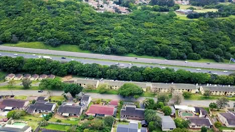 Imágenes-Aéreas-De-Un-Dron-Volando-Sobre-Casas-Residenciales-Con-Vistas-A-Una-Carretera-Muy-Transitada-Con-Tráfico-En-Movimiento-En-Un-Suburbio-De-Yellow-Wood-Park-En-Durban