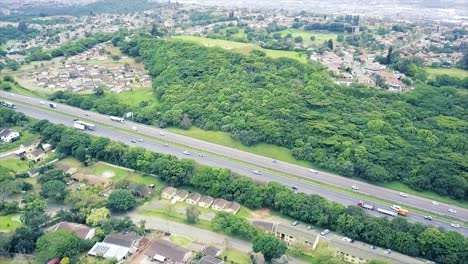 Imágenes-Aéreas-De-Un-Dron-Volando-Sobre-Casas-Residenciales-Con-Vistas-A-Una-Carretera-Muy-Transitada-Con-Tráfico-En-Movimiento-En-Un-Suburbio-De-Yellow-Wood-Park-En-Durban