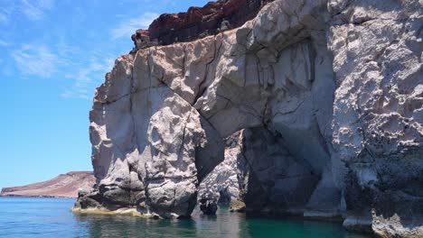 Boat-tour-exploring-Isla-Espiritu-Santo-passing-thru-a-rock-arch,-BCS