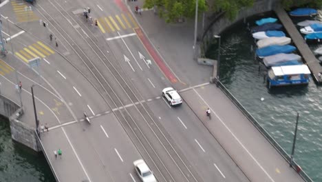 Toma-De-Arriba-Hacia-Abajo-Con-Un-Dron-Siguiendo-Un-Taxi-Blanco-Conduciendo-En-La-Ciudad-De-Zurich,-Suiza