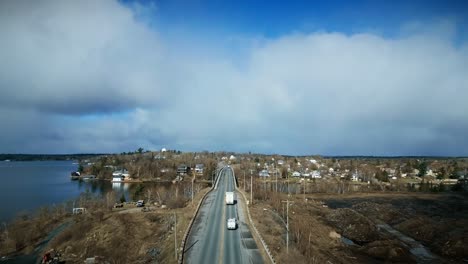 Drone-Shot-White-Truck-Drives-across-Elevated-Lake-Bridge-in-Countryside