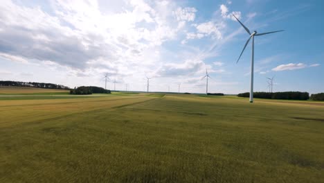 Campos-Verdes-Con-Turbinas-Eólicas-En-Un-Día-Soleado,-Vista-Aérea-Fpv