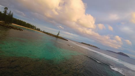 Shallow-reefs-at-sunset-as-orange-glow-on-clouds-in-Norfolk-Islands,-FPV-drone