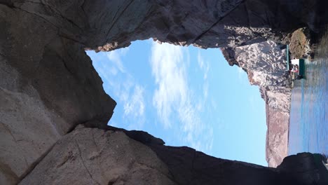 Boat-tour-exploring-Isla-Espiritu-Santo-passing-thru-a-rock-arch,-Baja-California-Sur