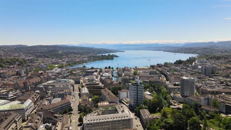 Drone-establishing-shot-over-the-city-of-Zürich-in-Switzerland-towards-lake-Zürich-on-a-hot-summer-day