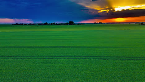 Hyperlapse-drone-shot-rising-over-rural-fields-with-dramatic-sunset-background