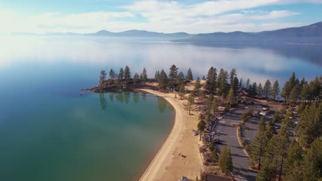 Sand-Harbor,-Lake-Tahoe-USA,-Aerial-View-of-Beach,-Park-and-Sky-Reflection-on-Calm-Water-on-Sunny-Winter-Day