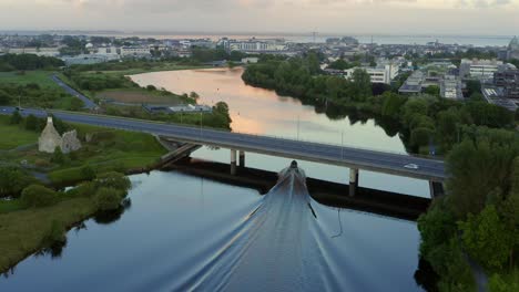 Inflatable-boat-leaves-long-wake-in-water-reflecting-beautiful-sunset-in-Galway-Ireland-on-the-River-Corrib