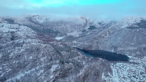 Drone-Se-Eleva-A-Lo-Largo-De-Las-Montañas-De-Bergen,-Noruega,-Ciudad-Cubierta-De-Capa-De-Nieve