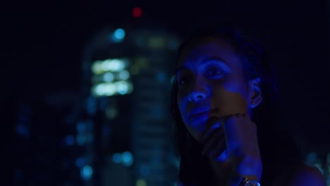 A-nighttime-rooftop-scene-features-a-young-girl-in-a-red-dress,-city-buildings-in-the-background