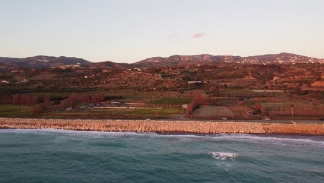 Drohnenaufnahmen-Eines-Ruhigen-Sonnenuntergangs-über-Einer-Küstenstraße-Auf-Zypern,-Mit-Sanften-Hügeln-Und-Dem-Mittelmeer-Im-Blick