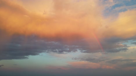 Nube-Naranja-En-El-Cielo-Con-Un-Pequeño-Arco-Iris-En-El-Costado-Durante-Una-Puesta-De-Sol