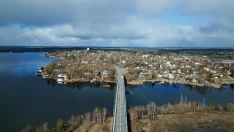 Un-Pequeño-Camión-Blanco-Cruza-Un-Gran-Puente-Sobre-El-Lago-En-Una-Zona-Rural