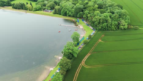 Aerial-footage-of-green-fields-beside-Cransley-Reservoir-in-Egland-during-daytime