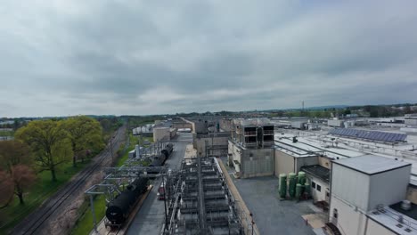 Aerial-flyover-industrial-factory-with-pipelines-and-silos-transport-on-railroad