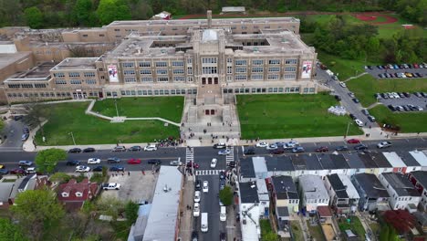 Aerial-approaching-shot-of-Students-leaving-high-school-after-dismissal